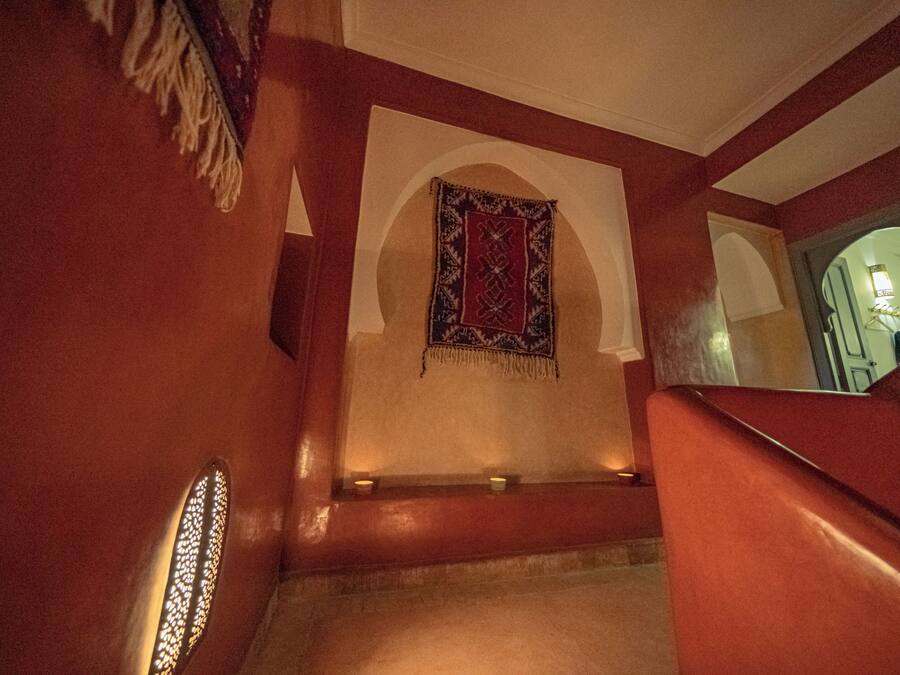 A staircase with a red wall and a patterned tapestry.