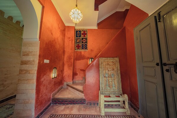 A staircase with a carpeted floor, a wooden chair, and a door.