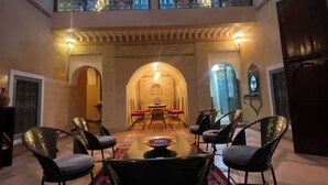 Un vaste espace dédié à la salle à manger, avec une longue table et des chaises, un tapis décoratif et une vue sur la cour.