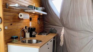 Pieni, käytännöllinen keittiö, jossa on puinen työtaso, pesuallas ja liesi.