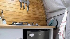 A compact kitchen with a built-in refrigerator, a wooden countertop, and a gas stove.