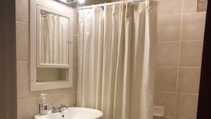 A bathroom with a white sink, mirror, and shower curtain. - Furnished efficiency for healthcare workers and executives in historic downtown. (Hannibal)