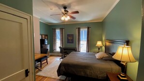 A bedroom with a bed, desk, chair, and a ceiling fan. - Furnished efficiency for healthcare workers and executives in historic downtown. (Hannibal)