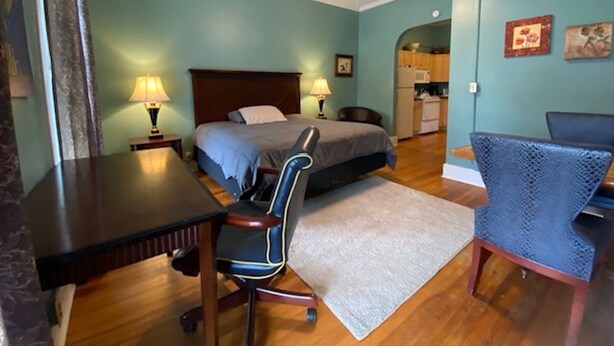 A bedroom with a bed, desk, chair, and a ceiling fan. - Furnished efficiency for healthcare workers and executives in historic downtown. (Hannibal)