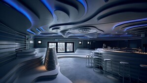A modern bar area with a curved seating arrangement and a central stack of plates. - Villa Viva Hotel Hamburg (Hamburg)