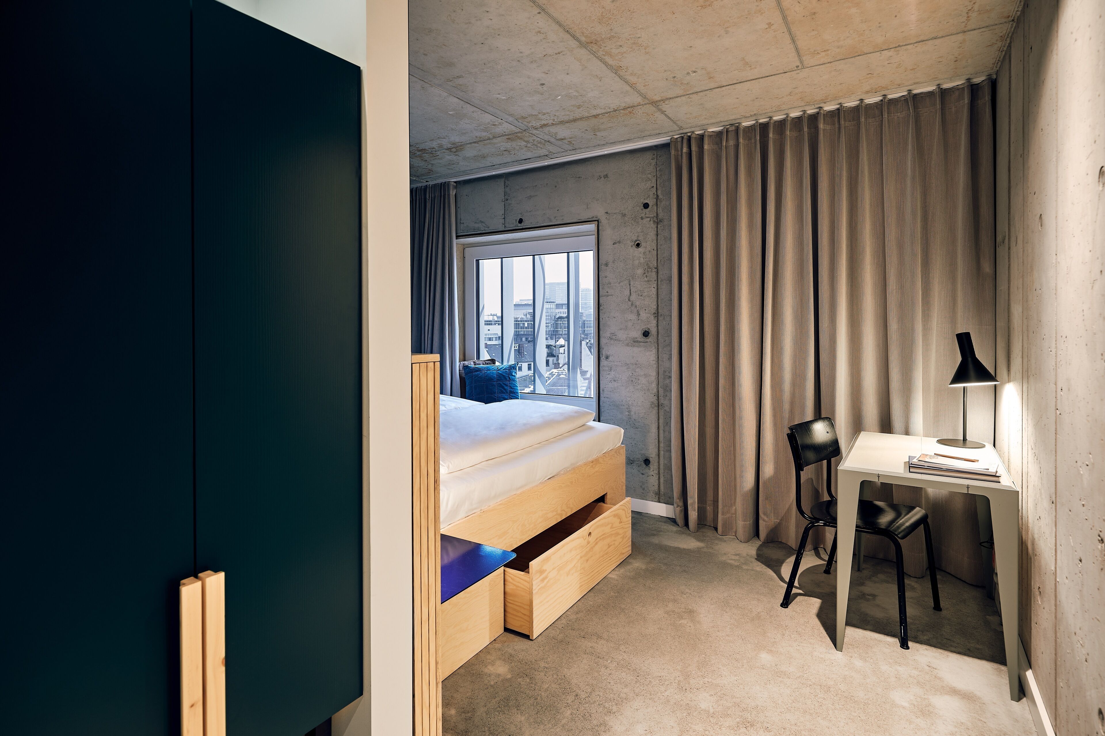 Un dormitorio compacto con cama, escritorio y silla.