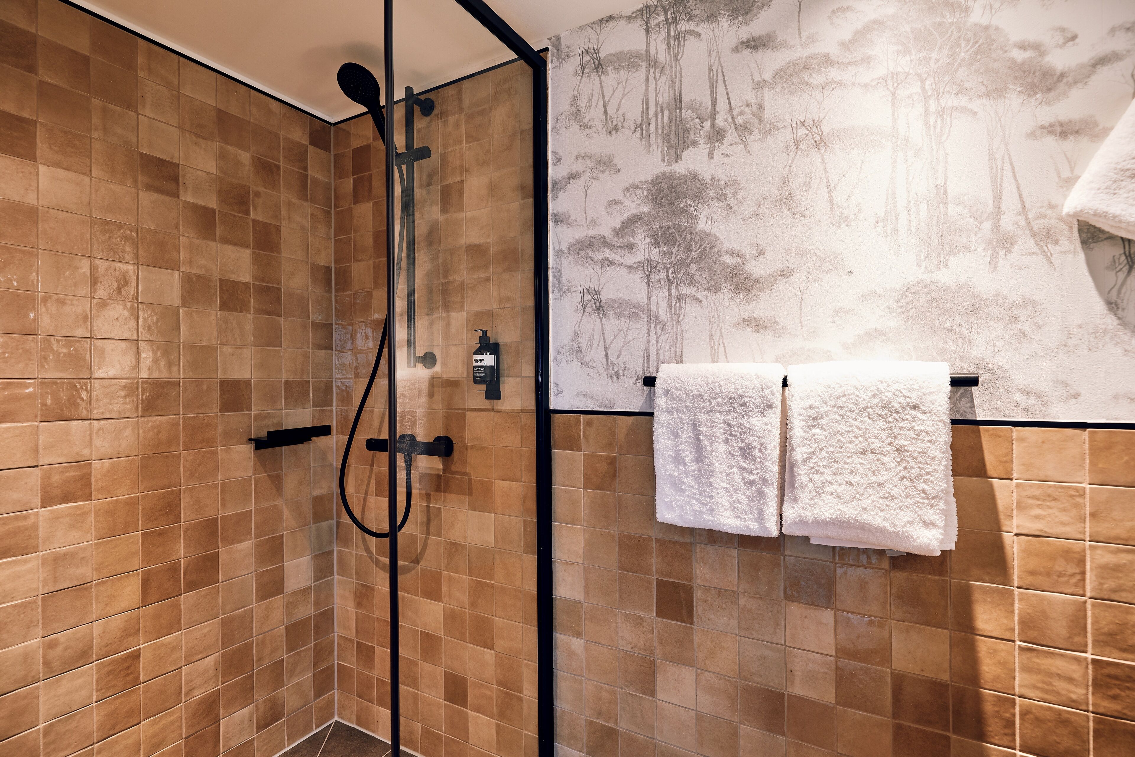 Un espace douche avec des murs carrelés et un pommeau de douche.