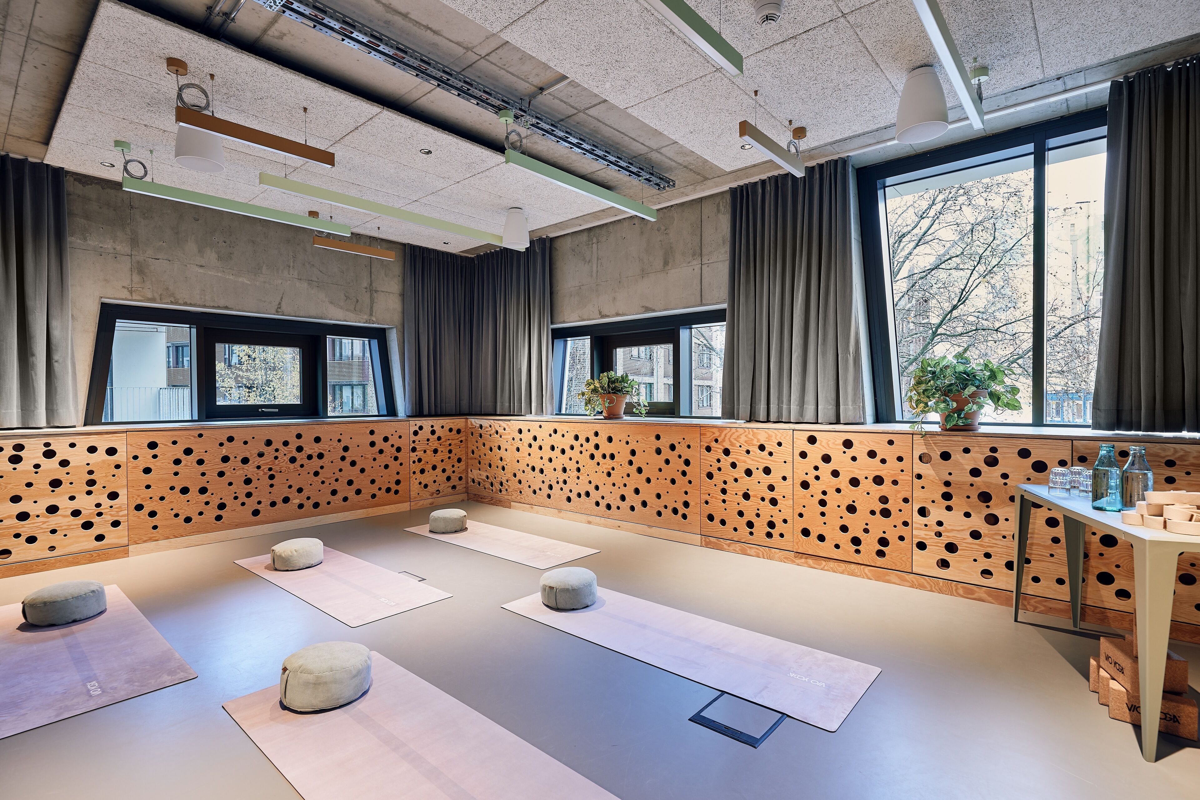 Un studio de yoga doté de tatamis, de touches de bois et de grandes fenêtres.