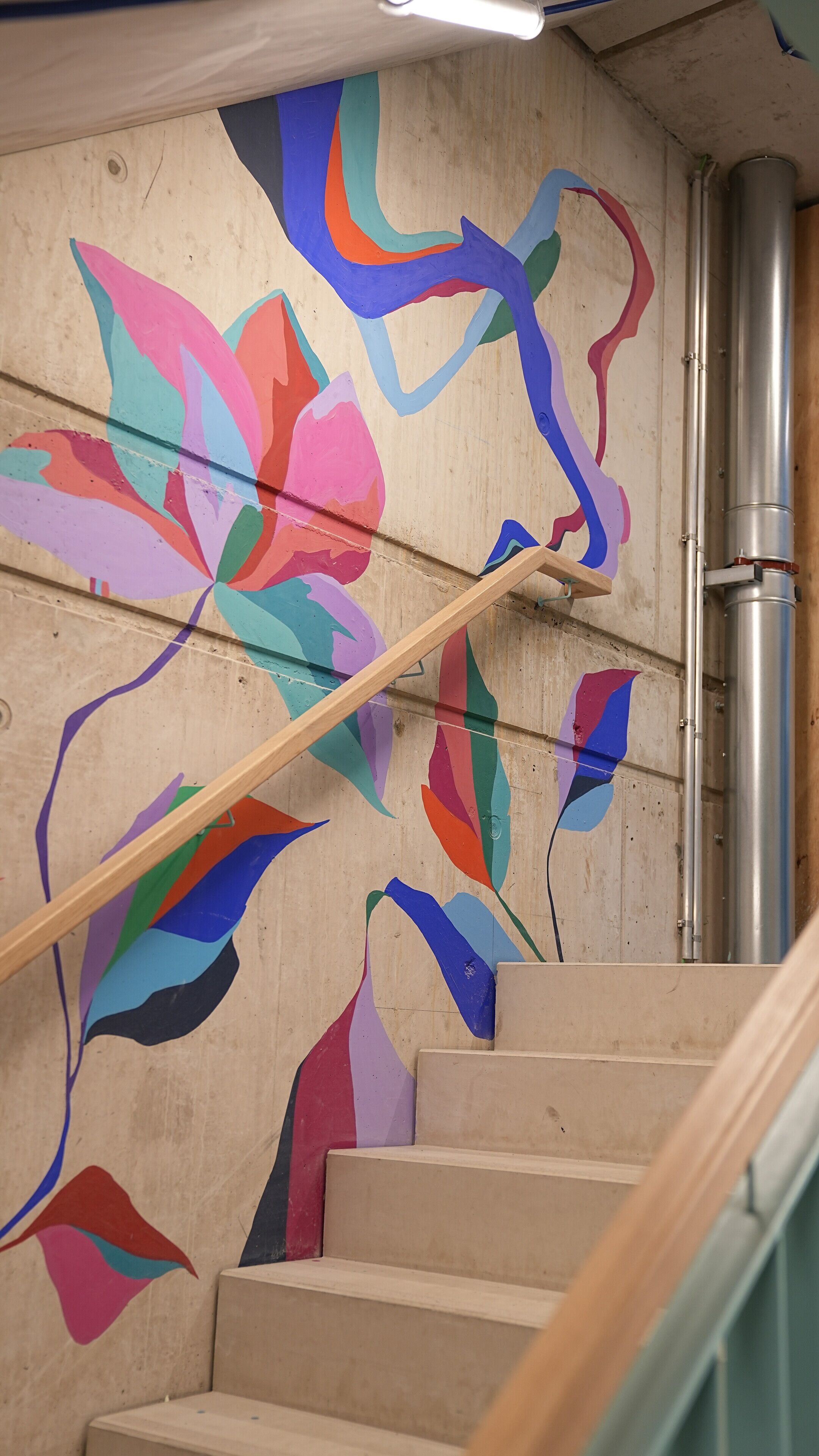 Un escalier orné d’une fresque murale abstraite et colorée.