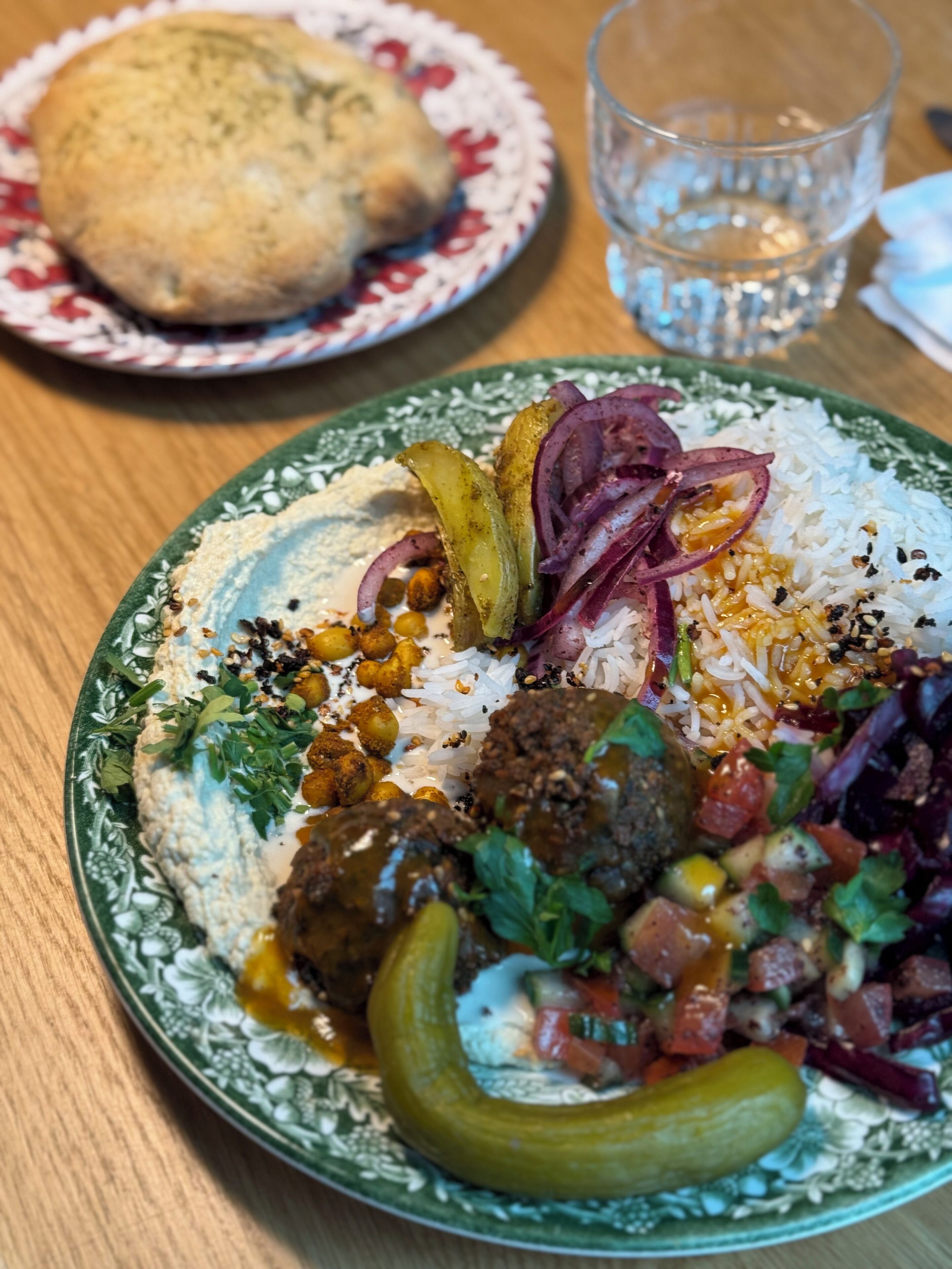 A plate of food with rice, meatballs, vegetables, and a side of bread.