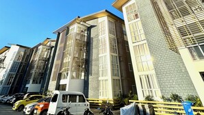 A modern building with multiple floors, large windows, and a parking area with various vehicles. - Escape to Paradise: Unwind in Style at our Spectacular Haven (Lapu-Lapu City)