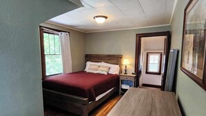Un dormitorio con una cama de madera, una mesita de noche, un escritorio y una ventana con cortinas.
