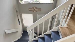 Una escalera con barandillas blancas y escalones azules que conduce a una plataforma con un letrero que dice 'Beach House'.