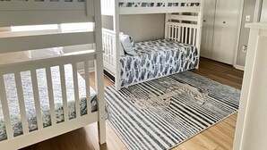 Una habitación con literas, ventilador de techo y alfombra estampada.