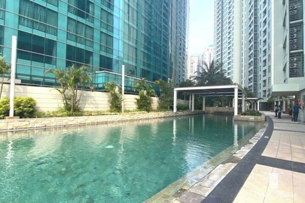 Relax by the pool surrounded by a walkway and a modern building with large windows.