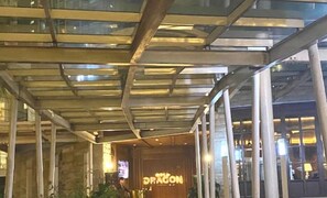Welcome to the Dragon hotel, featuring a sleek glass canopy and stone facade.