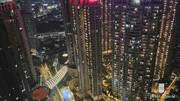 A high-rise building with multiple floors, illuminated windows, and a prominent curved structure at the base. - Impressive City View Suit for 4 Persons (West Jakarta City)