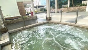 A hot spring area with a stone pool, metal railings, and a paved walkway. - Impressive City View Suit for 4 Persons (West Jakarta City)