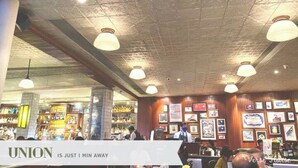A bar area with a sign reading "UNION IS JUST I MIN AWAY" and a ceiling with exposed beams and pendant lighting. - Impressive City View Suit for 4 Persons (West Jakarta City)