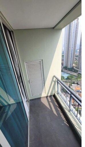 Un balcón con vista a edificios altos y una piscina.