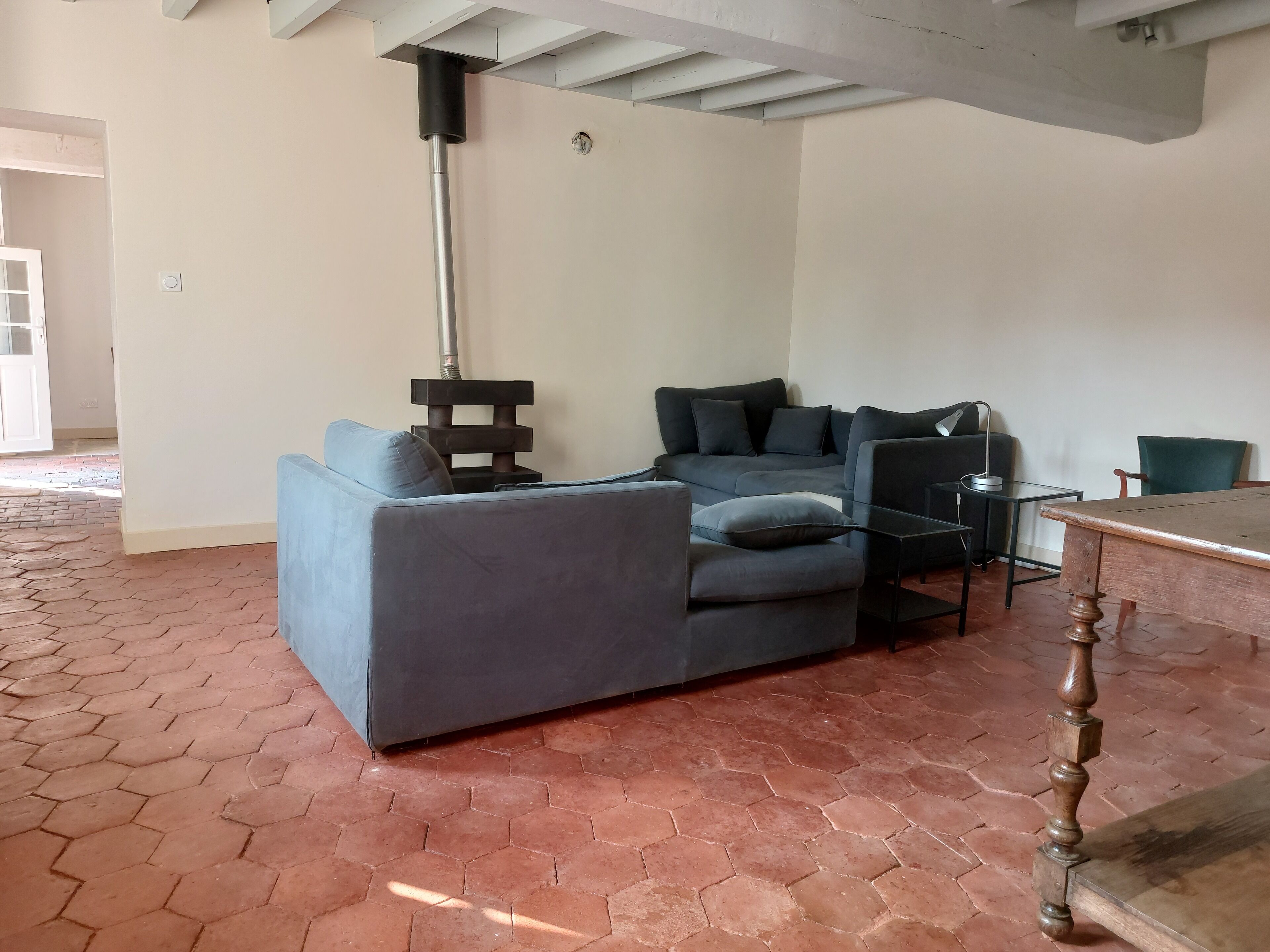 Una sala de estar moderna con un sofá gris, una mesa de centro de cristal y una mesita auxiliar de madera.