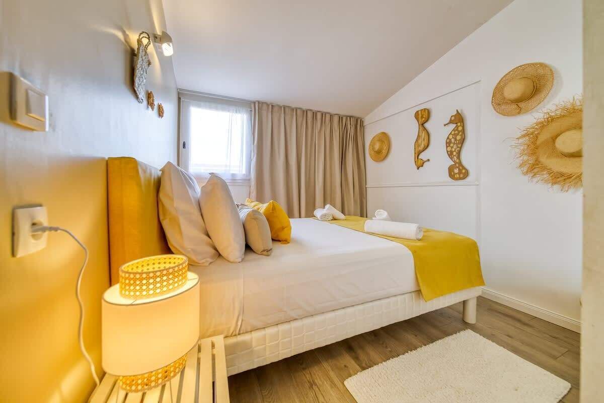 A bedroom with a bed, pillows, a lamp, and wall decorations.
