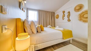 Een slaapkamer met een bed, kussens, een lamp en decoraties aan de muur.