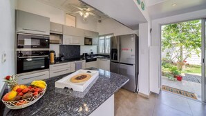 Een moderne keuken met roestvrijstalen apparatuur, een granieten aanrechtblad en uitzicht op de achtertuin.