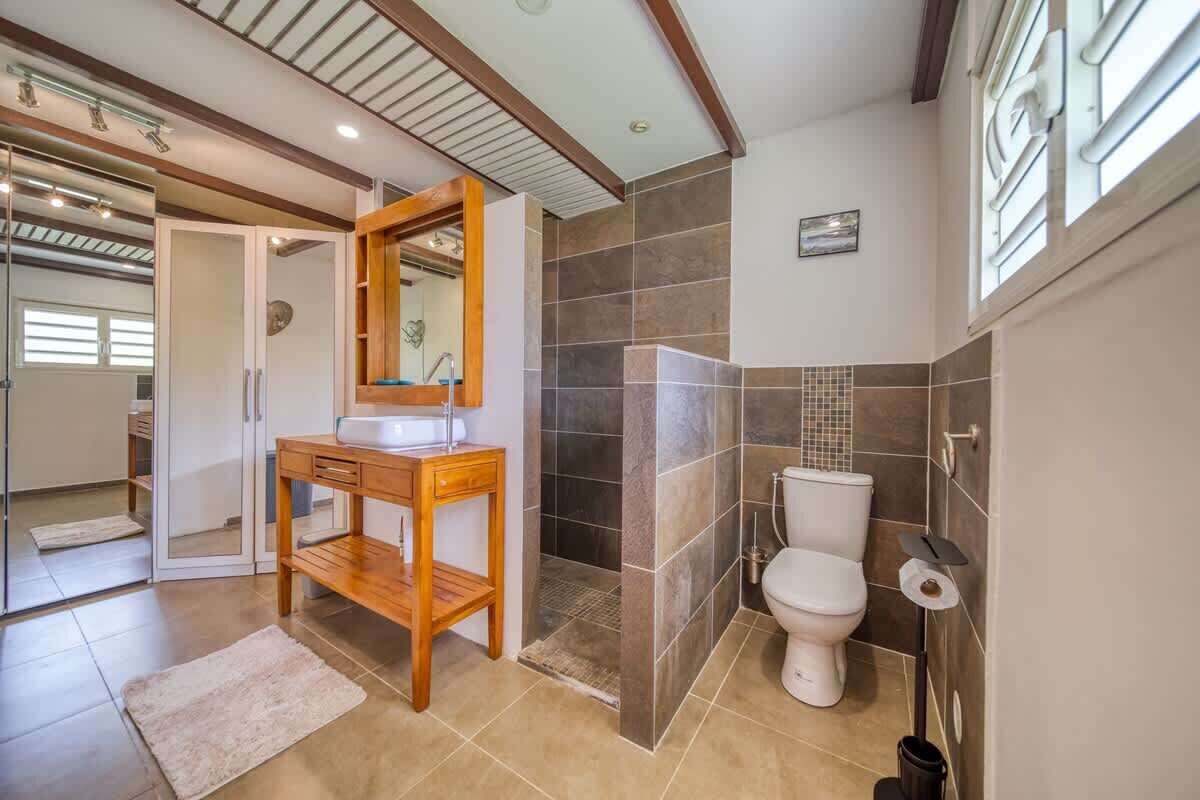 A bathroom with a wooden vanity, a shower enclosure, and a toilet.