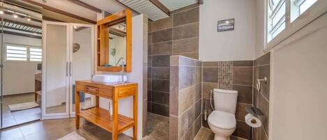 A bathroom with a wooden vanity, a shower enclosure, and a toilet.