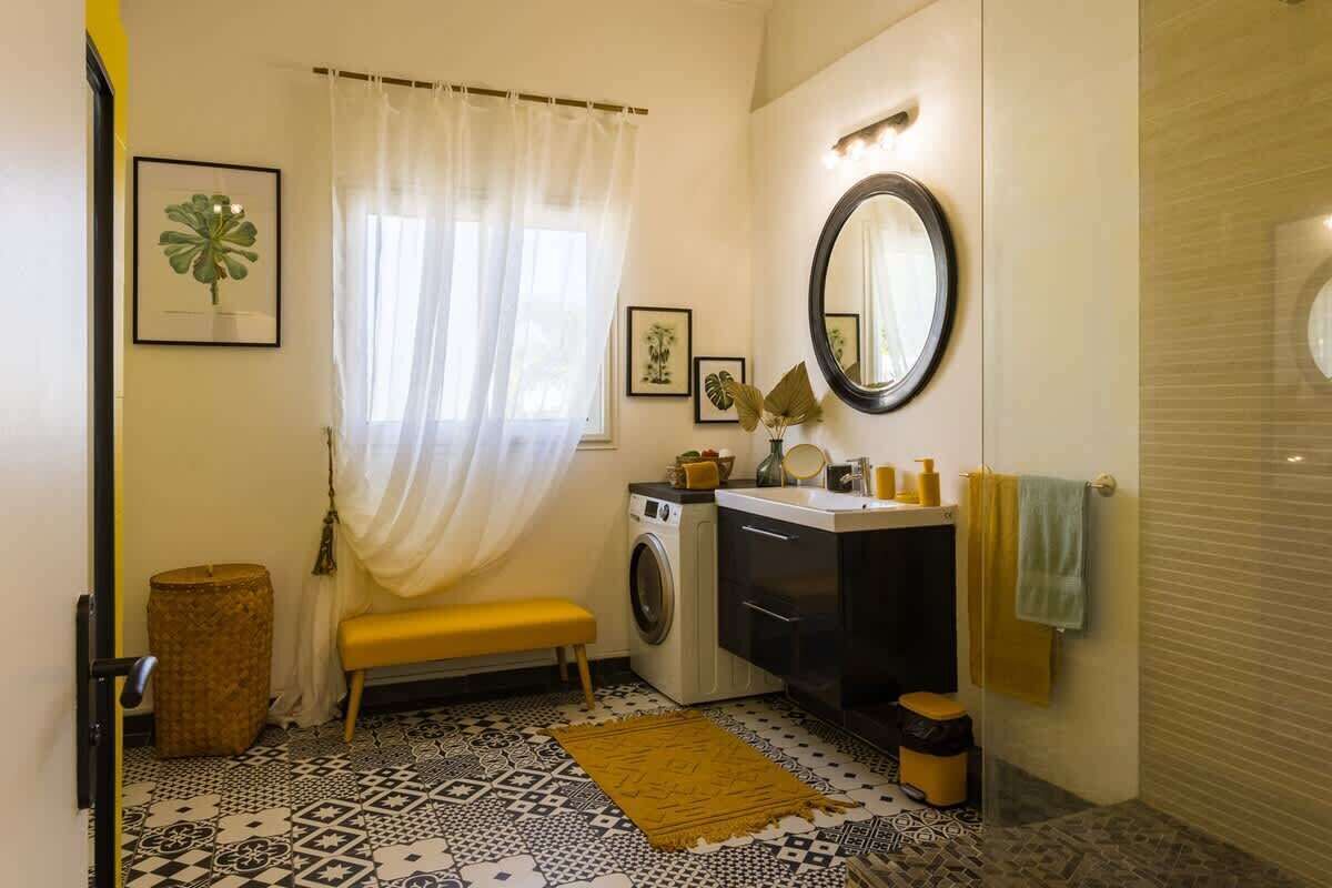 Une petite salle de bain équipée d’un lave-linge, d’un évier, d’un miroir et d’un banc.