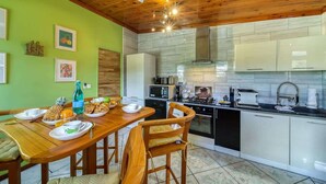 Une cuisine moderne avec des meubles en bois, une table à manger avec des chaises et un mur vert.