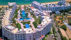 Un resort con piscina central, varias edificaciones y una playa al fondo.