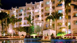 Un hotel con varios balcones, piscina y palmeras.