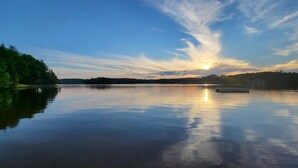 A calm lake at sunset with a clear sky, a dock, and trees along the shore. - Northwoods Lodge Hotel Room 2 (Long Lake)