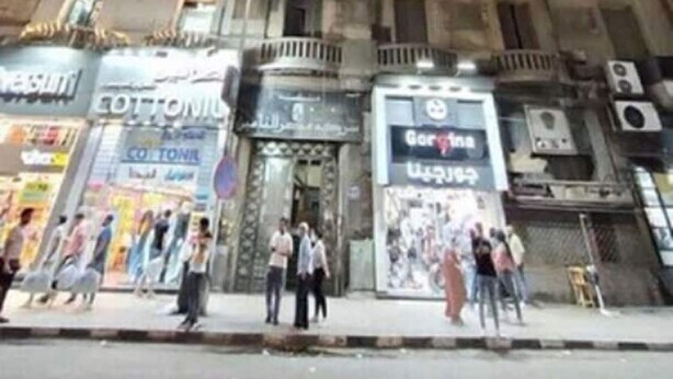 A multi-story building with several ground-floor shops, including a visible sign for 'Cotton'. - New Panorama Palace (Cairo)