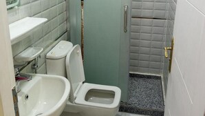 A small, compact bathroom with a toilet, sink, and shower area. - New Panorama Palace (Cairo)