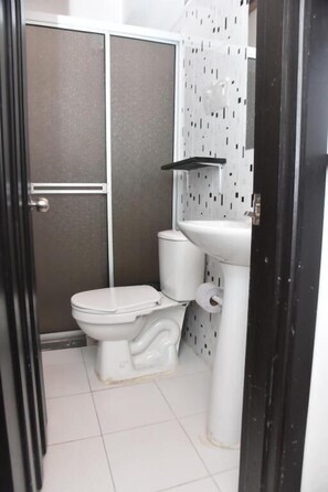 Un baño con inodoro, lavabo y zona de ducha.