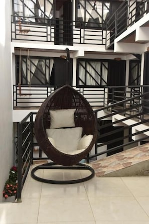 Un interior moderno con una silla colgante esférica única, una escalera y un balcón con barandillas.
