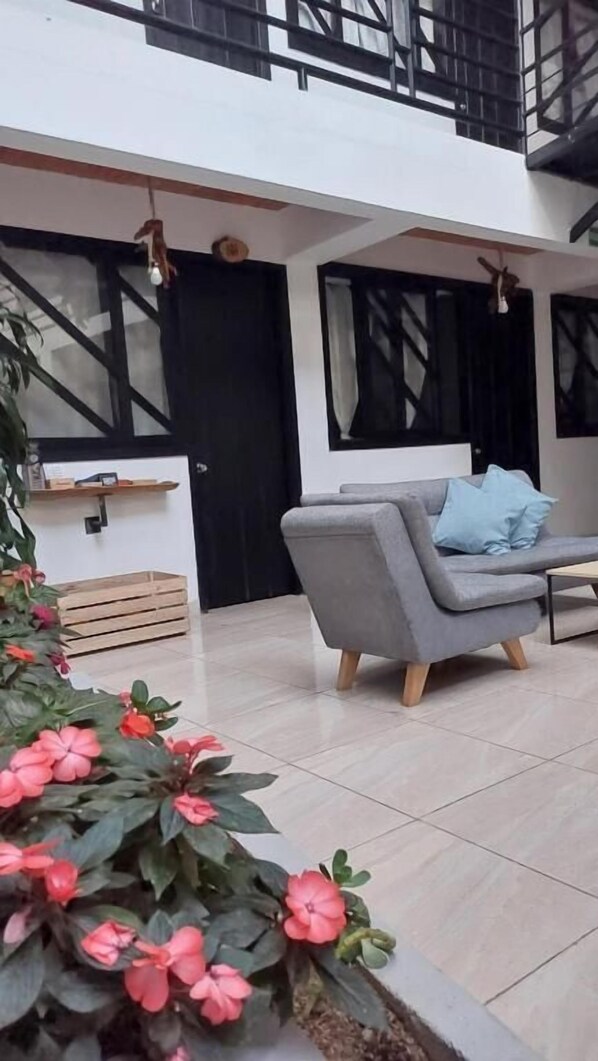 A modern living room with a grey sofa and a coffee table, a staircase, and a black door. - Hotel Samai (San Agustin)