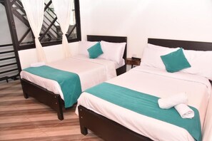 Dos camas individuales con ropa de cama blanca y turquesa, un cabecero de madera y una escalera con barandilla negra.