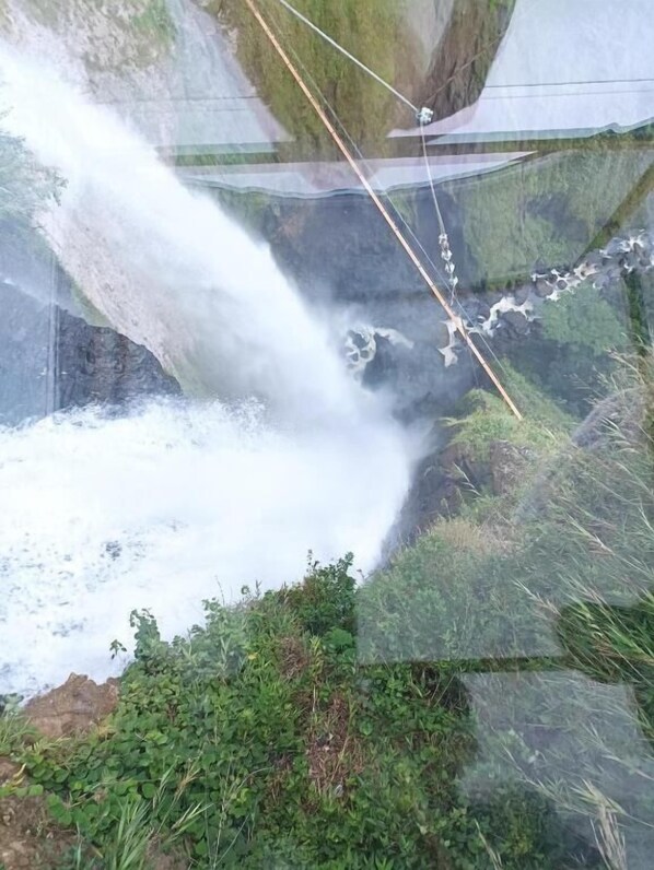 Una cascada se precipita sobre un acantilado rocoso con una zona de observación transparente.