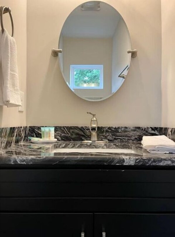 Une salle de bain avec un lavabo en marbre, une petite fenêtre et un porte-serviettes.