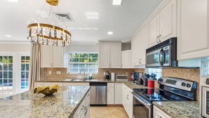 A modern kitchen with granite countertops, stainless steel appliances, and white cabinetry.
