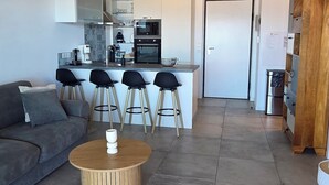 Un salon moderne avec un canapé, une table basse et une cuisine en arrière-plan.