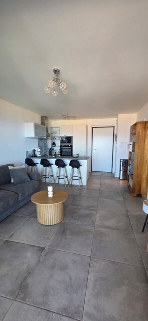 Un salon moderne avec un canapé, une table basse et une cuisine en arrière-plan.