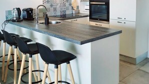 Une cuisine moderne dotée d’un îlot central, de tabourets de bar, d’un four à micro-ondes, d’un four traditionnel et d’un évier.