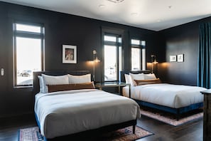 A hotel room with two beds, large windows, and a view of the street. - The Hotel Melrose (Grand Junction)
