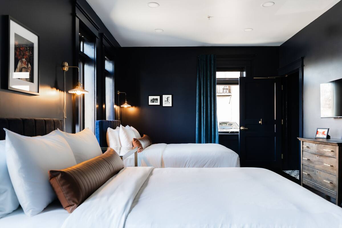 A hotel room with two beds, a dresser, and a door leading to a balcony.