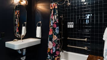 A modern bathroom with a white sink, a mirror, a shower curtain with floral patterns, and a bathtub.